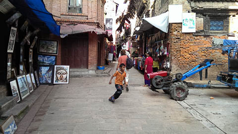 A boy runs past one of many tractors in Bhaktapur